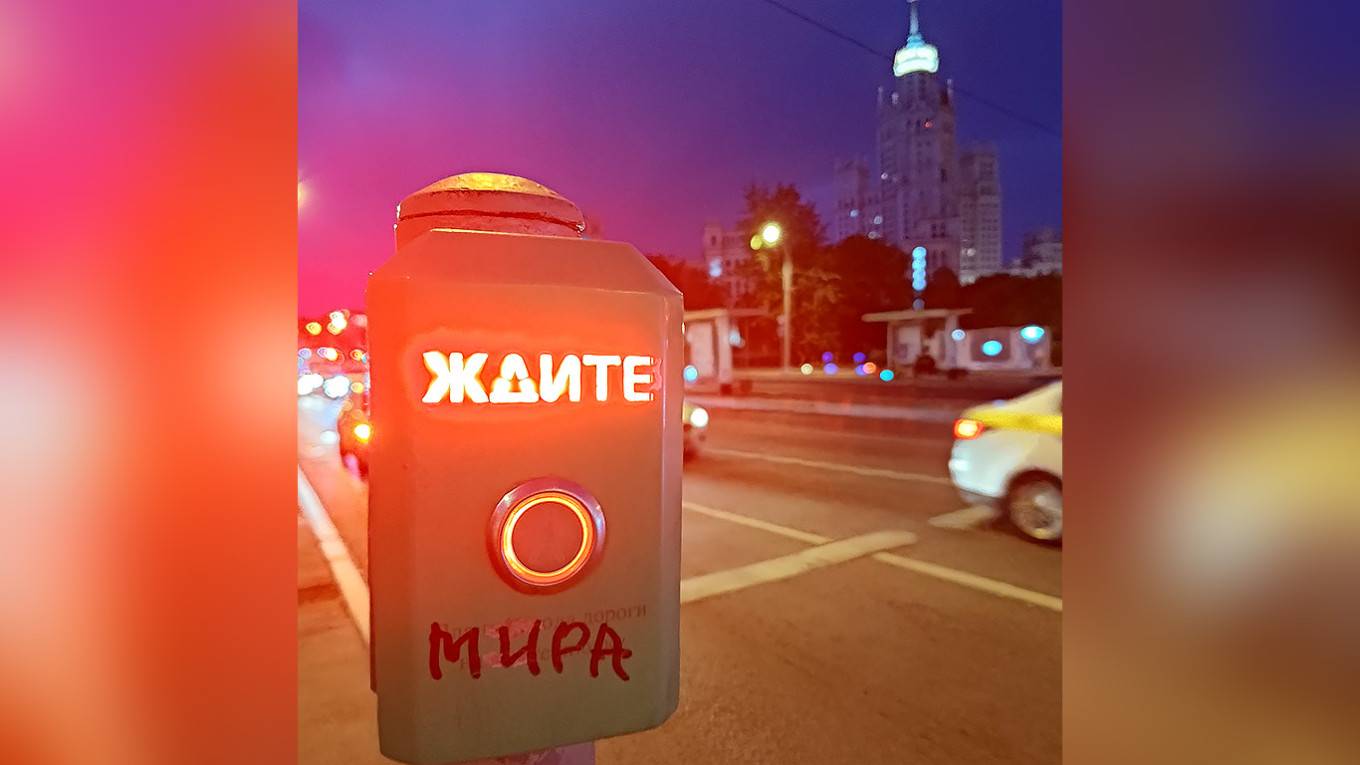 
					A pedestrian crossing button at a traffic light in Moscow with the word "Wait," where someone has added "Mira" ["for peace"], making it read "Wait for peace."					 					MT				